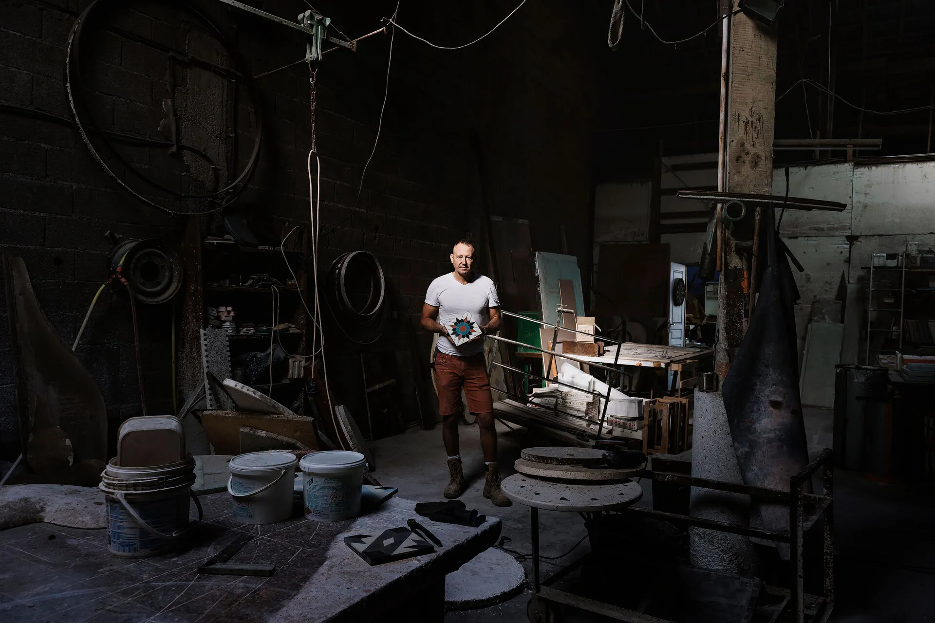 David Dalichoux tenant un de ses carreaux de ciments ua milieu de son atelier