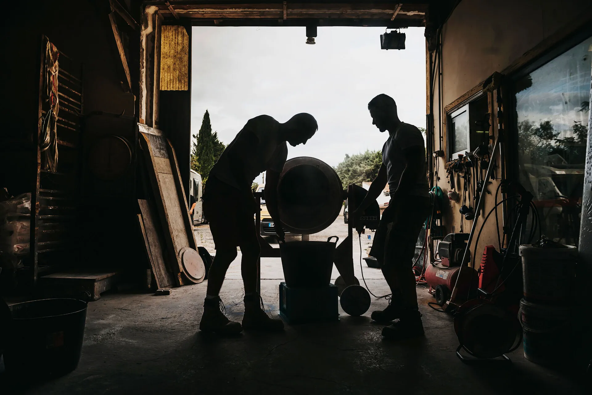 silhouette de deux hommes travaillant autour d'une bétonnière dans l'atelier