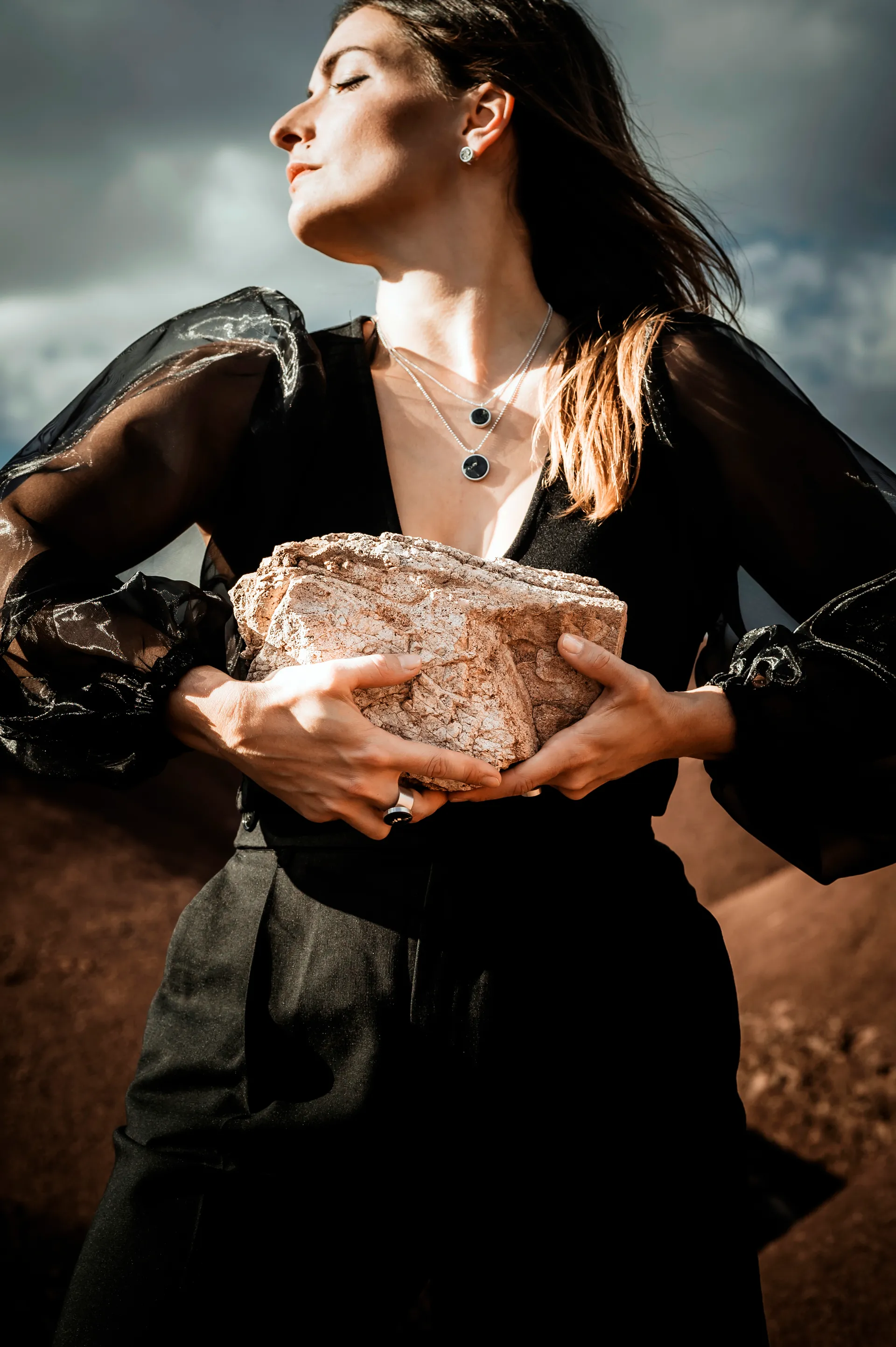 femme en robe noire portant une pierre, une bague au doigt et un collier autour du cou