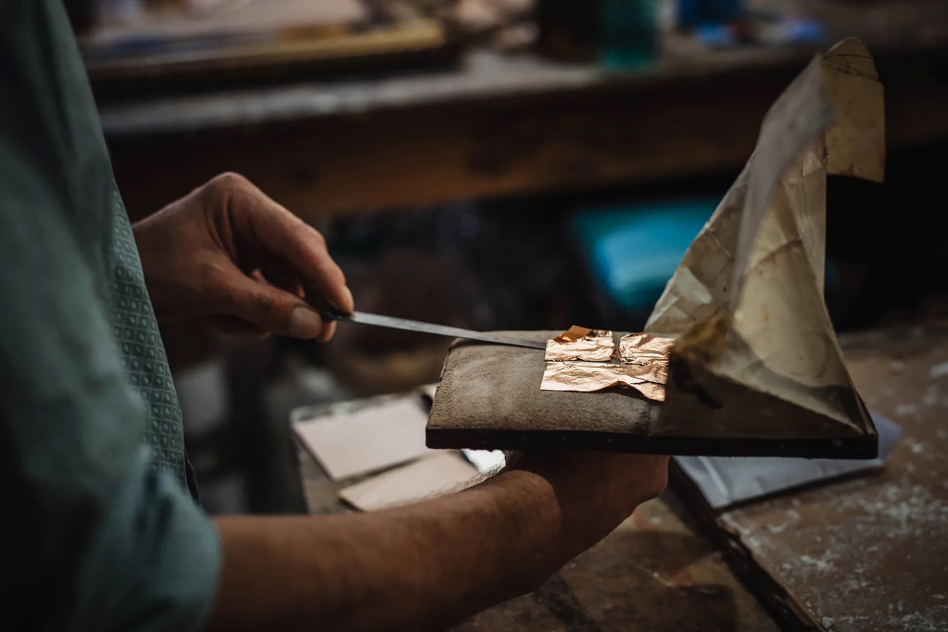 gros plan sur l'artisan manipulant des feuilles d'or avec un couteau