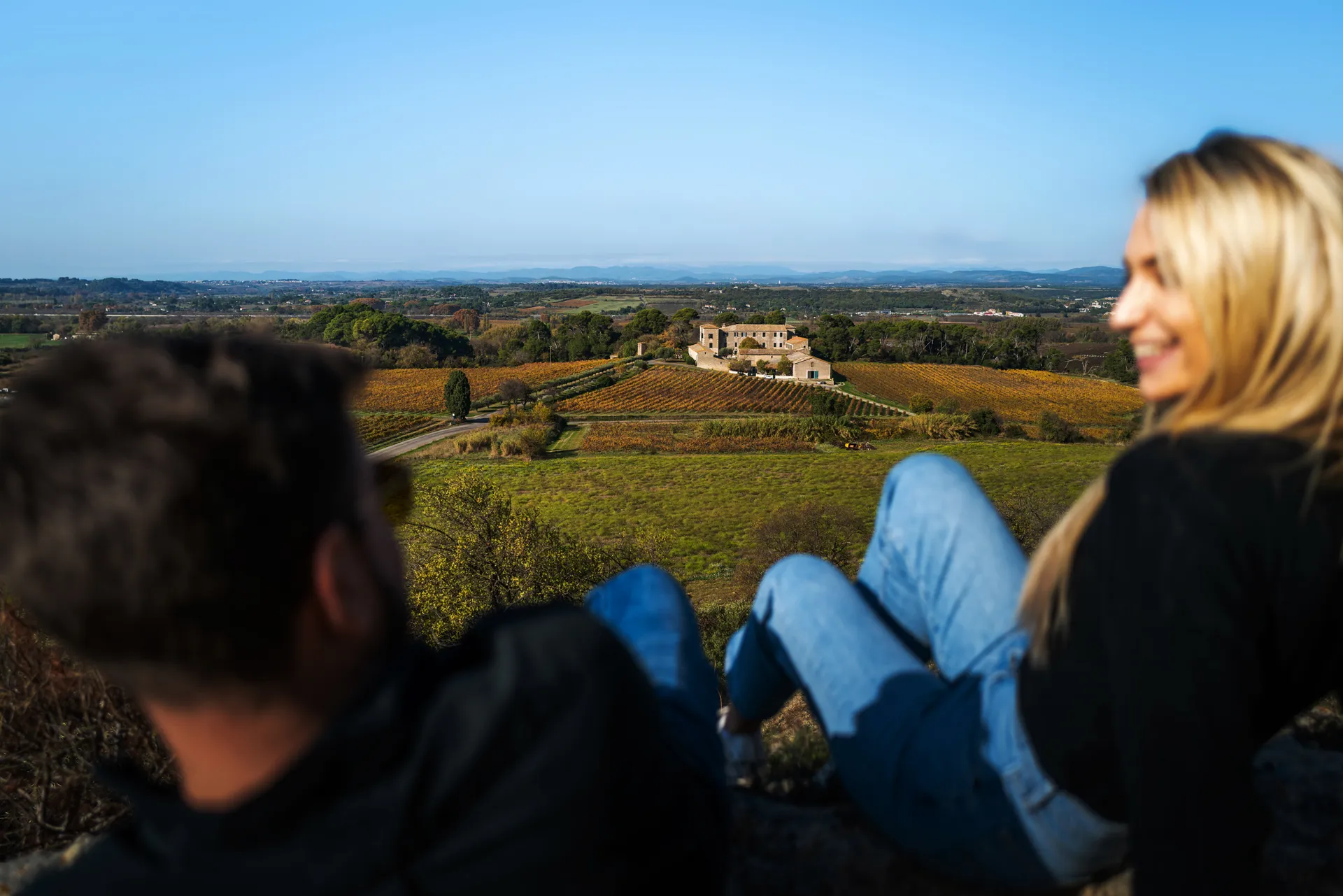 un couple assis dans l'herbe avec une vue sur une demeure viticole